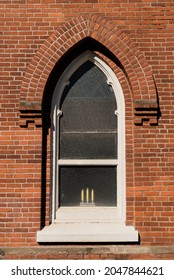 Three candles symbolizing the father, the son and the holy spirit in the window of an old brick church.