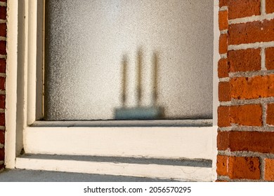 Three candles symbolizing the father, the son and the holy spirit in the window of an old brick church.