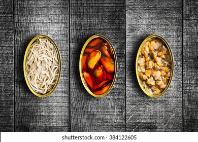 Three canned food above grunge wooden table. Top view.