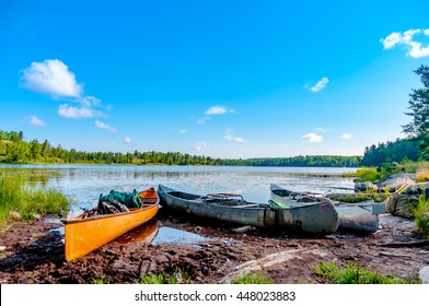 Three canoes on the shore of a lake in the Boundary Waters Canoe Area in the North Woods of Northern Minnesota wait for the paddlers to return from a portage. 