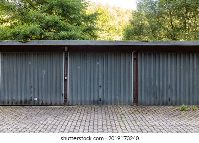 A Three Car Garage Standing Alone On A Roadside. A Rustic Old Garage With Steel Doors. Symmetry In The Architecture. 