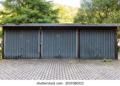 A Three Car Garage Standing Alone On A Roadside. A Rustic Old Garage With Steel Doors. Symmetry In The Architecture. 