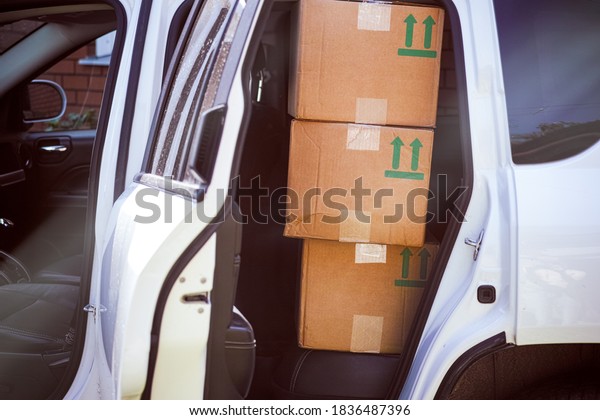 Three\
cardboard boxes on the back seat of white\
car.