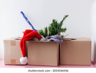 Three cardboard boxes one contains an artificial Christmas tree Santa hat and wrapping paper.