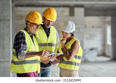 Three caucasian engineers discussing over digital tablet on the construction site - Shutterstock ID 2112413999