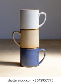 Three ceramic mugs stacked vertically by color.