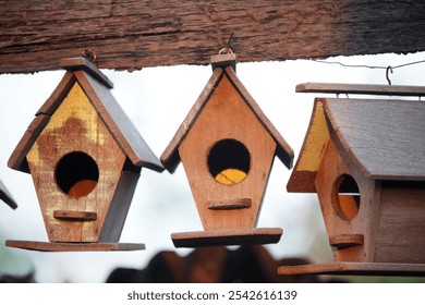 Three charming wooden birdhouses hang in a rustic setting, showcasing natural materials and warm tones, perfect for enhancing any garden or outdoor space. - Powered by Shutterstock