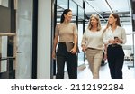 Three cheerful businesswomen walking together in an office. Diverse group of businesswomen smiling while having a discussion. Successful female colleagues collaborating on a new project.