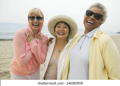 Three cheerful multiethnic female friends laughing on the beach