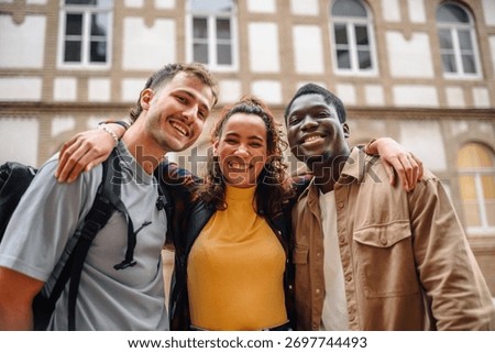 Three cheerful multi-ethnic students embracing outside university, enjoying their time together