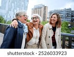 Three cheerful only mature Caucasian friends women enjoying walking happy together in urban park. Older gray hair tourists female people strolling laughing European sightseeing holidays outdoors 