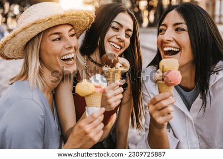 Three cheerful teenage women eating ice cream cones on city street - Happy female tourists enjoying summer vacation in Italy - Summertime holidays