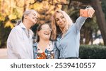 Three cheerful women, including one with down syndrome, taking a selfie outdoors, celebrating friendship and inclusion