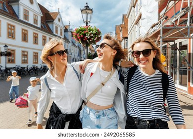 Three cheerful young adult women friend with kids walk street old european german town city street enjoy having fun laughing sunny day together. Female persons friendship celebration party weekend - Powered by Shutterstock