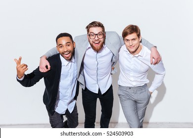 Three Cheerful Young Men Standing And Smiling Together Over White Background