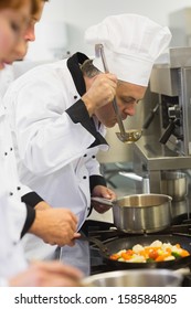 Three Chefs Working At The Stove In Commercial Kitchen