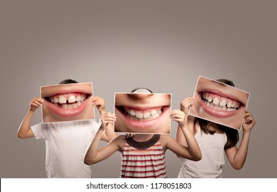 tres niños sosteniendo una foto de una boca sonriendo