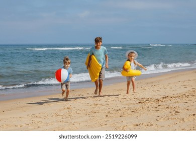 Three children joyfully run along the beach, one holding a beachball and another with an inflatable ring - Powered by Shutterstock