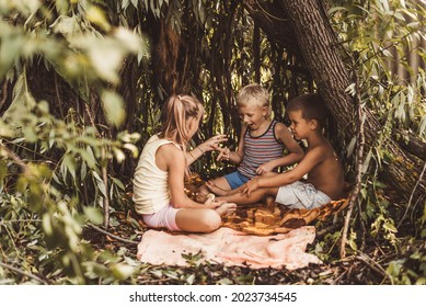 Three children play in a hut which they themselves have built from leaves and twigs.