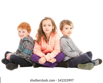 Three Children Sitting Cross Legged On Floor Waiting Patiently. On White.