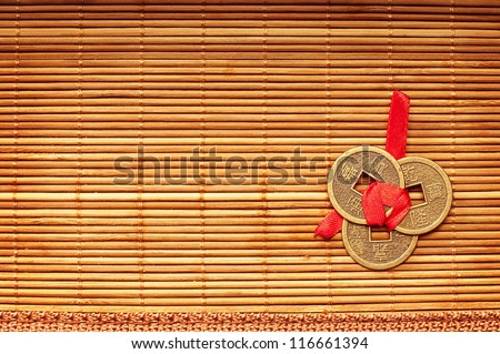 Three Chinese lucky coins tied with red ribbon on wooden mat
