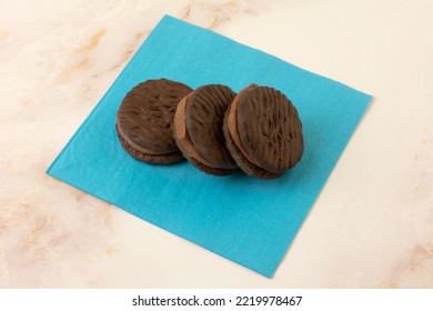 Three Chocolate Fudge Sandwich Cookies On Blue Snack Napkin On Table