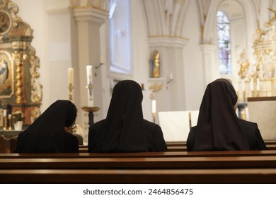 three Christian Nuns, Seen From Behind, Looking At The Church Altar. Traditional Black Clothes. 