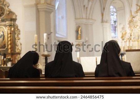 three Christian Nuns, Seen From Behind, Looking At The Church Altar. Traditional Black Clothes. 