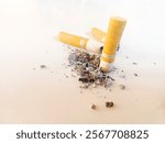 three cigarette butts with ash scattered on a white surface