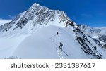 Three climbers are walking on a snow-covered mountain slope. Climbing Belukha. Altai Mountains. View of mountain ranges, hills and peaks. Beautiful snowy winter landscape.