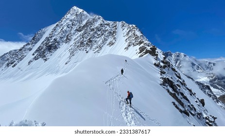 Three climbers are walking on a snow-covered mountain slope. Climbing Belukha. Altai Mountains. View of mountain ranges, hills and peaks. Beautiful snowy winter landscape.