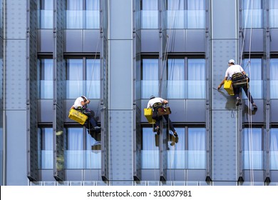 Three climbers wash windows and glass facade of the skyscraper 