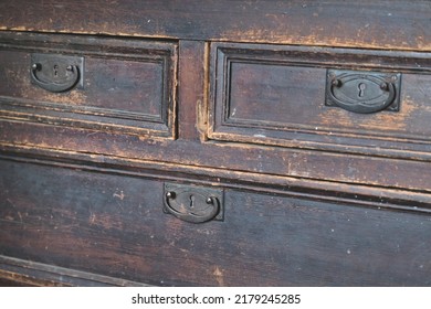 three closed drawers of an old retro chest of drawers with vintage furniture, a metal rustic handle with a false lock closeup