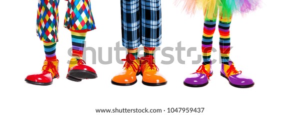 Three clowns legs in clown shoes of different colors isolated on white