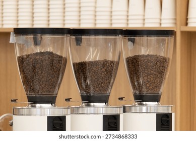 Three coffee grinders are lined up next to each other, each filled with a different amount of coffee beans