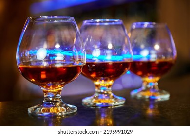 Three Cognac Glasses With Cognac On The Bar