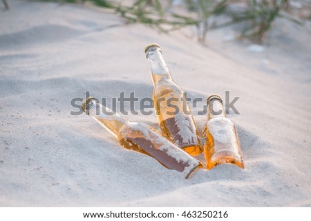 Three cold beer bottles in the warm sand