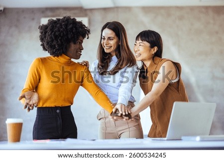 Three colleagues actively collaborating and sharing ideas in a bright office setting, embracing teamwork and diversity in a professional environment.