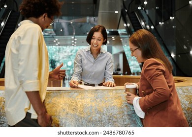 Three colleagues chat and laugh together in a modern office lobby - Powered by Shutterstock