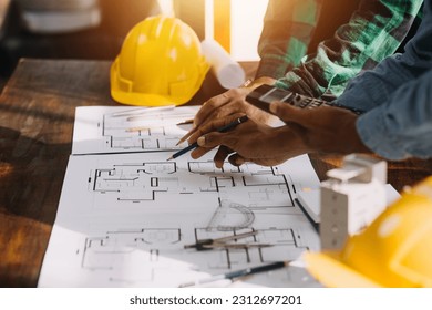 Three colleagues discussing data working and tablet, laptop with on on architectural project at construction site at desk in office