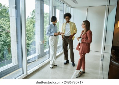 Three colleagues, including a woman with a prosthetic leg, stand by a window in a modern office, holding coffee cups and chatting. - Powered by Shutterstock