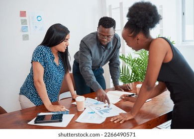 Three colleagues stand around conference table meeting about financial reports strategy - Powered by Shutterstock