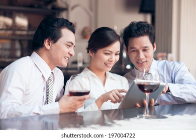 Three colleagues using digital tablet in the bar - Powered by Shutterstock