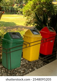 Three color-coded trash cans red yellow green standing in a bright lobby for waste segregation and recycling