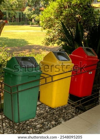 Three color-coded trash cans red yellow green standing in a bright lobby for waste segregation and recycling