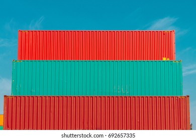 Three colored containers stacked in a port seen from side