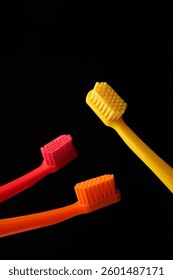 Three colored plastic toothbrushes on a black background. Oral hygiene of the mouth. Dentist.