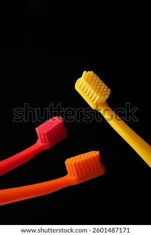 Three colored plastic toothbrushes on a black background. Oral hygiene of the mouth. Dentist.