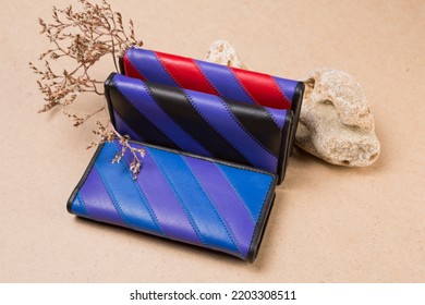 Three Colored Women's Leather Wallets Are Located On A Natural Background, With A Bush And A Stone, Still Life