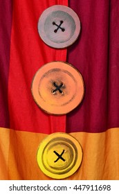 Three colorful buttons / pins / knobs in a column on red and orange fabric